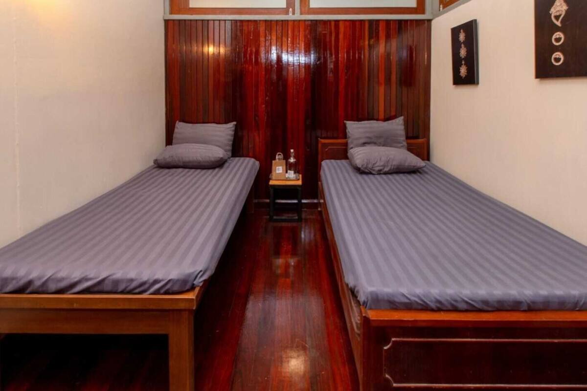 A room with two single beds, wooden flooring, and a wooden headboard.