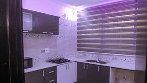 A modern kitchen with dark cabinets, white countertops, and a built-in stove. - Stunning 3-bed House in Lagos (Lagos)