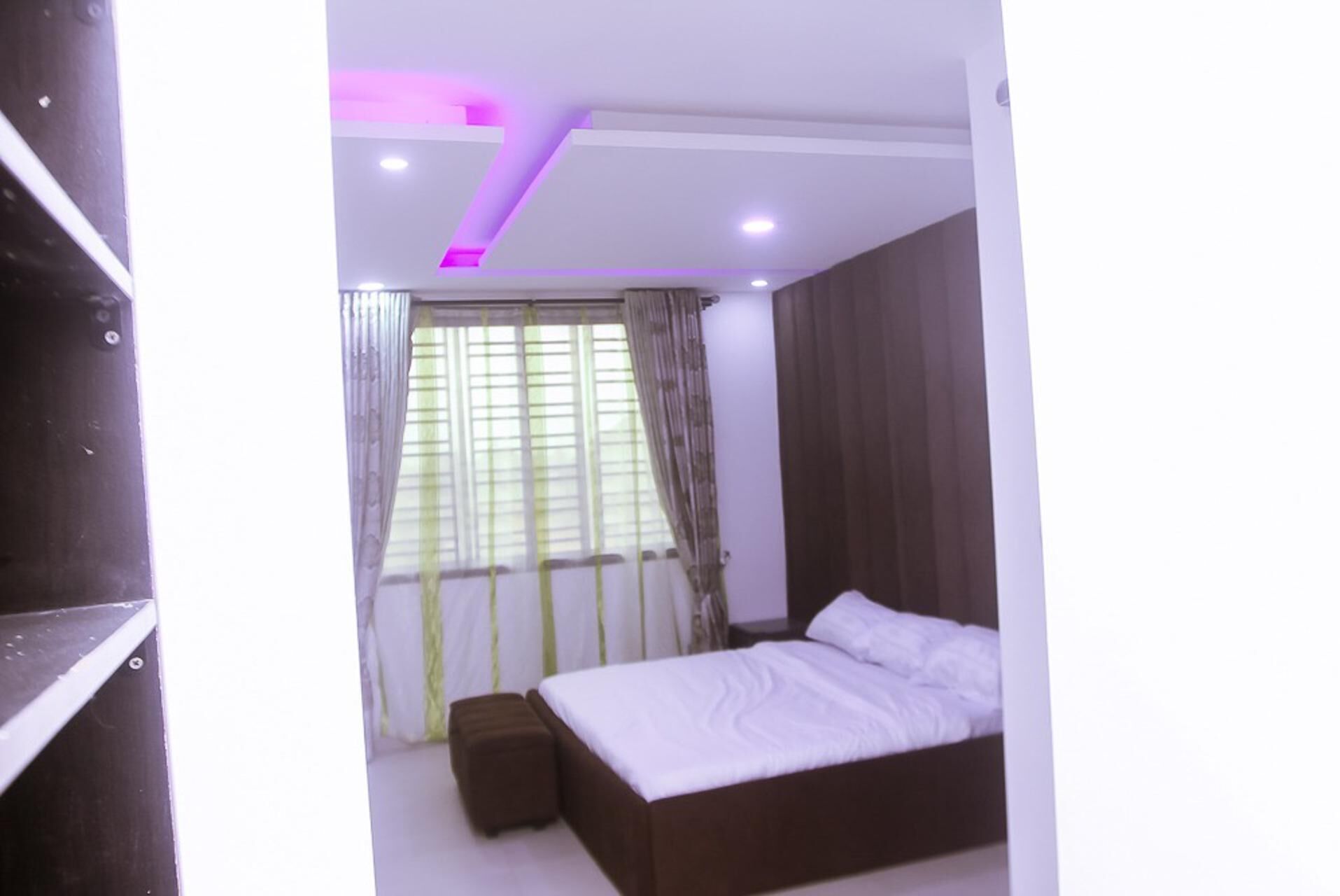 A bedroom with a bed, a window with curtains, and a ceiling with recessed lighting.