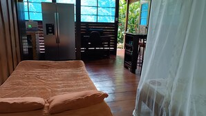 Ein Zimmer mit einem Bett, einem Kühlschrank und einem Fenster mit Blick auf Grünflächen.