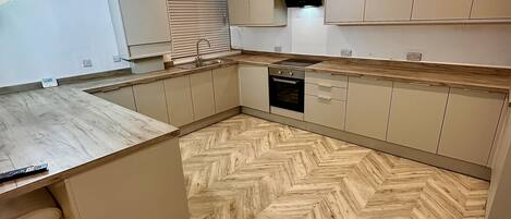 Una cocina moderna con piso de madera en espiga, armarios empotrados y una isla central.