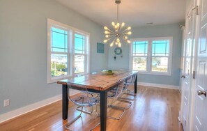 Un comedor con una mesa de madera, sillas de metal y una lámpara moderna.
