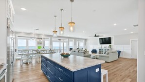 A spacious kitchen with a large island, wooden flooring, and a view of the ocean. - Experience beachfront luxury at Seaclusion, Oak Island's 10-bedroom retreat. (Oak Island)