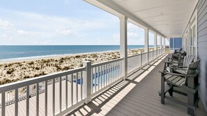 A covered porch with a view of the beach and ocean. - Experience beachfront luxury at Seaclusion, Oak Island's 10-bedroom retreat. (Oak Island)
