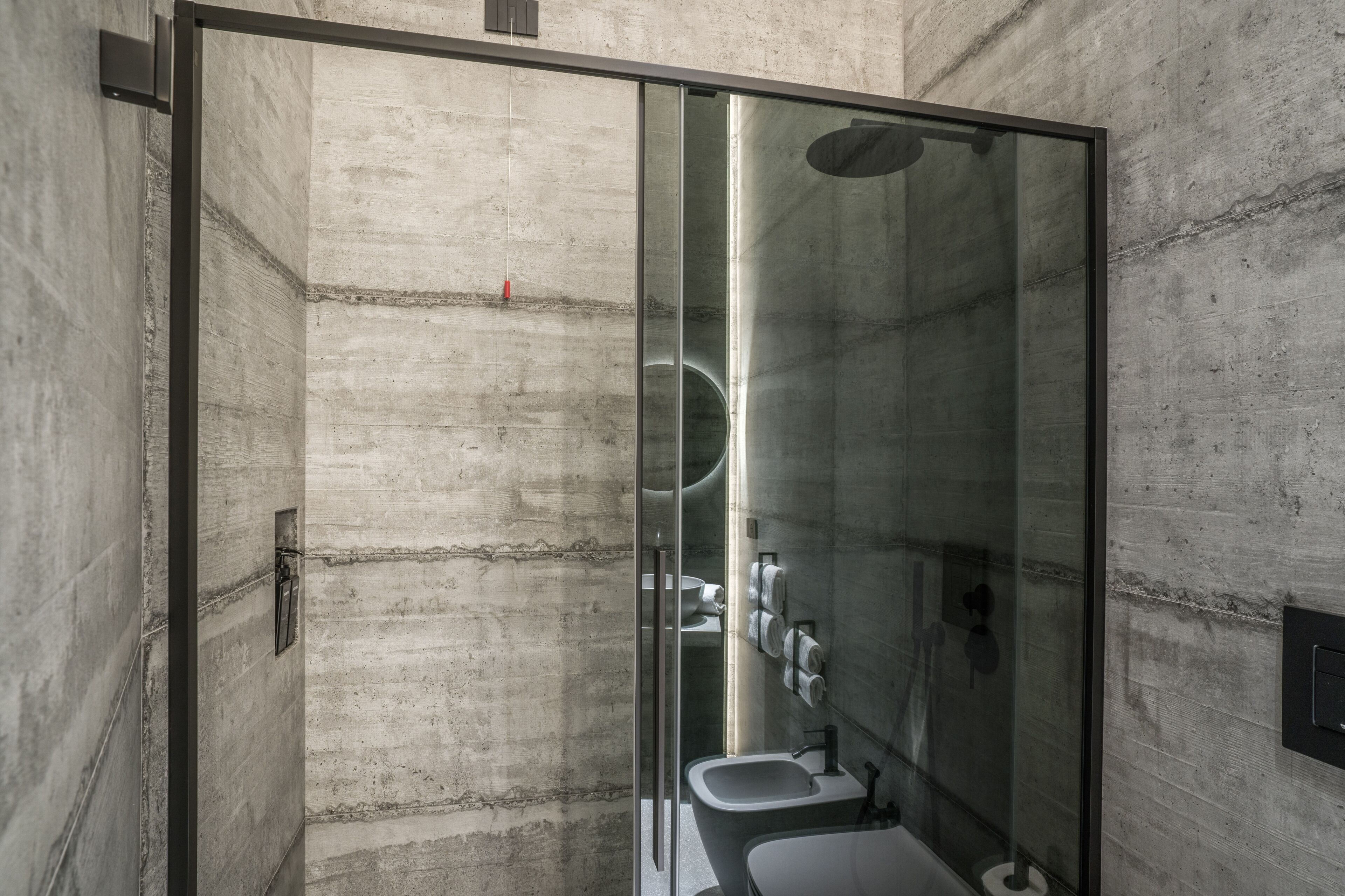 A modern bathroom with a glass shower enclosure, a toilet, and a sink.