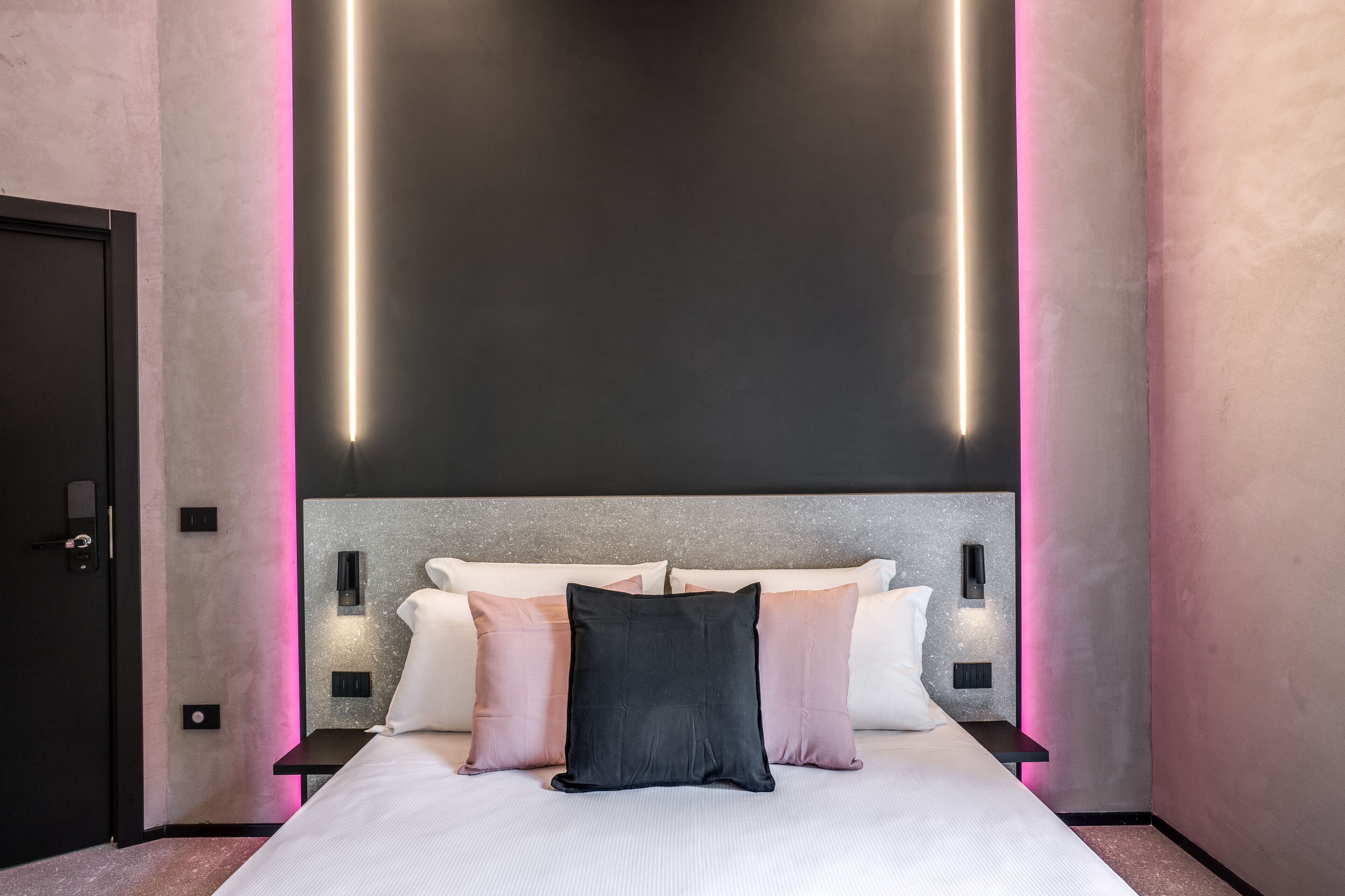 Een moderne slaapkamer met een groot bed, een hoofdeinde met ingebouwde verlichting en een minimalistisch design.