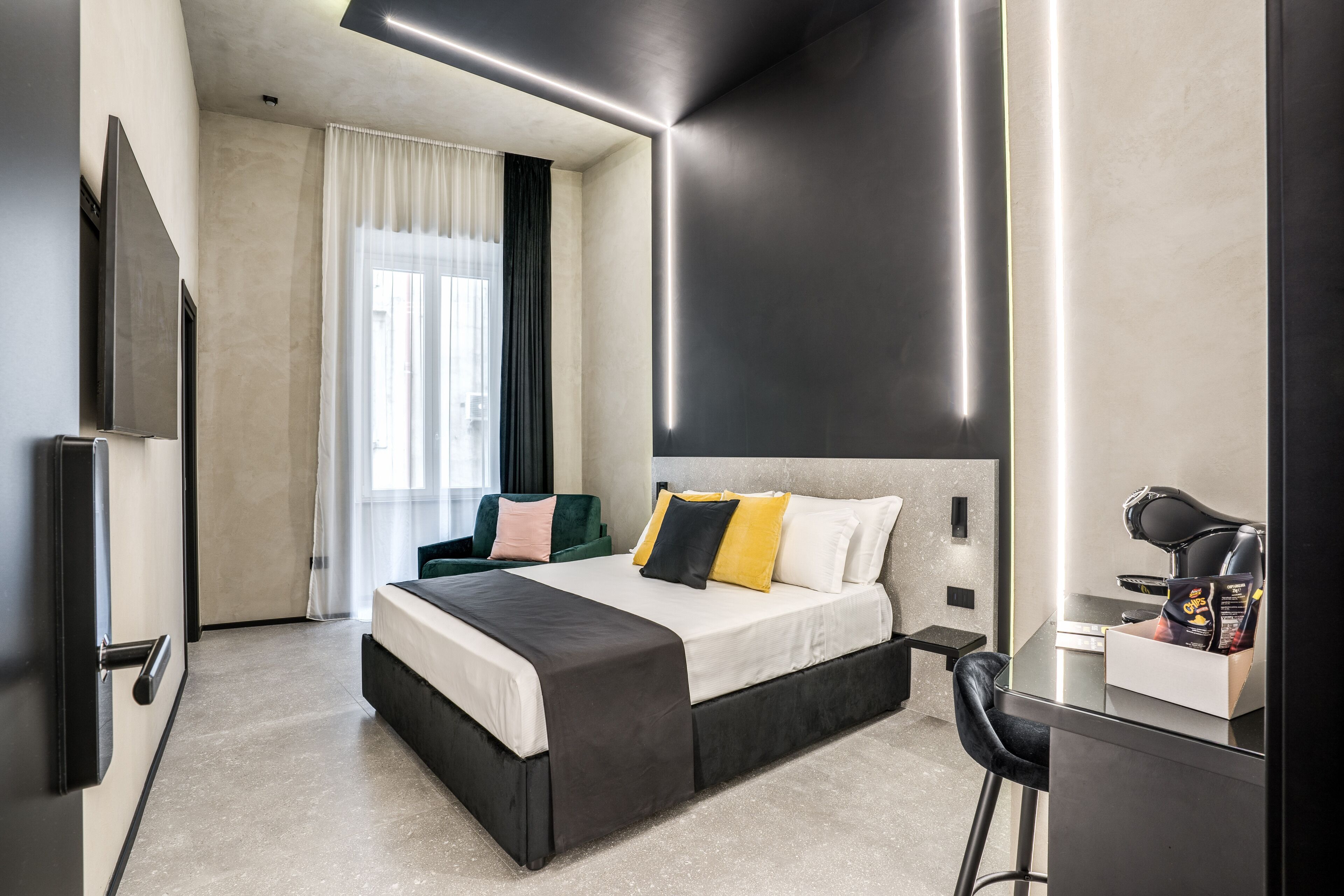 Una moderna camera d'albergo con un letto grande, una scrivania con una sedia, una TV a schermo piatto e una finestra con tende.