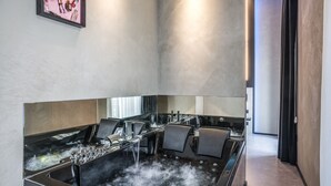 A modern spa with a large hot tub, seating area, and a framed artwork on the wall. - Gallery Experience Napoli (Naples)