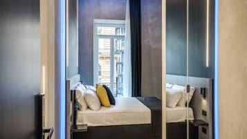 A modern bedroom with a large bed, bedside tables, and a view of the city through a window.