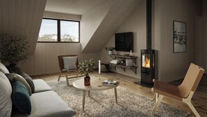 A cozy loft bedroom with a sloped ceiling, a fireplace, a TV, and a comfortable seating area with a sofa and chairs. - Tännäskröket (Tannas)