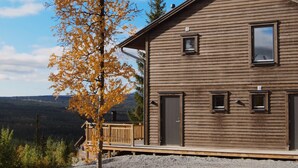 A wooden cabin with a deck, a mountain backdrop, and a clear sky. - Tännäskröket (Tannas)