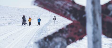 A snowy ski slope with skiers and a ski lift in the background.