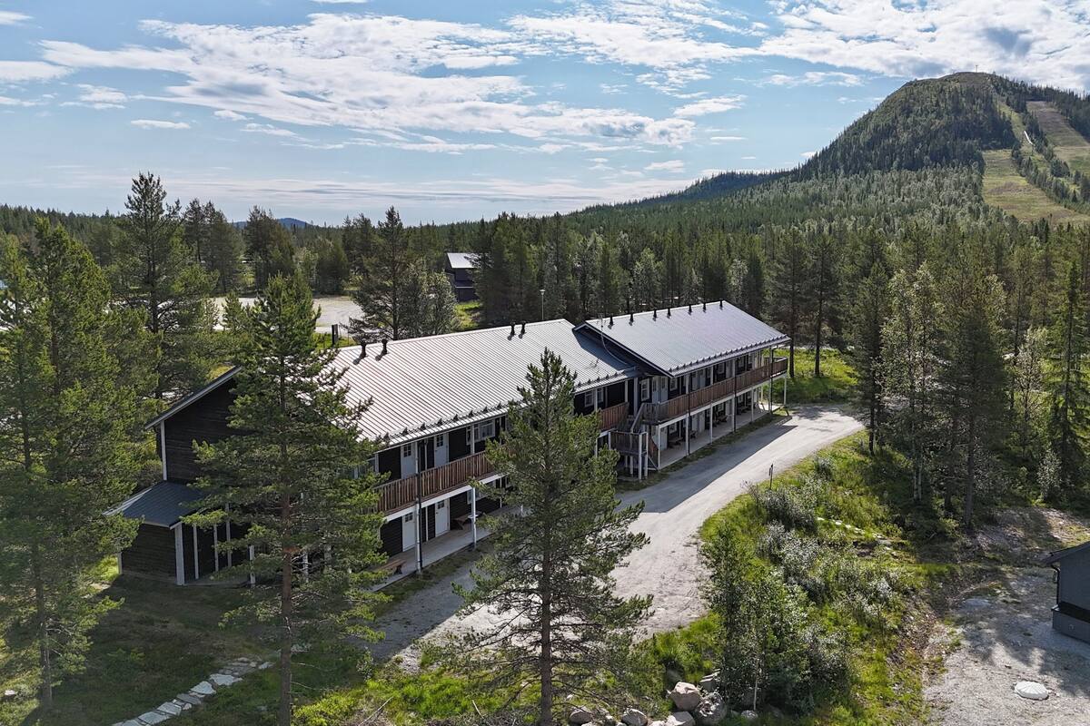 A lodge with a long building, a smaller structure, and a mountain backdrop.