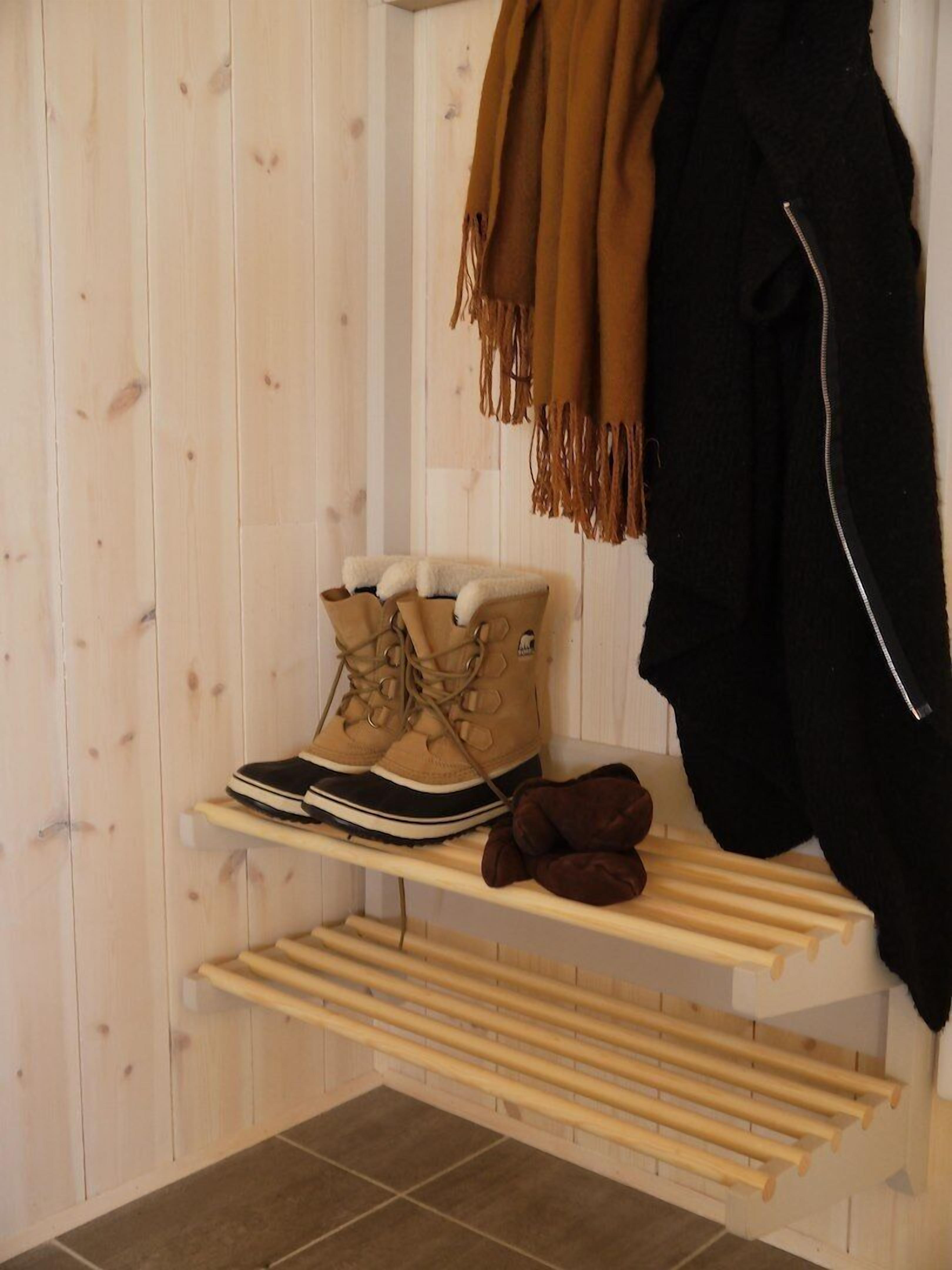 A wooden shelf with a pair of beige boots and a brown scarf.