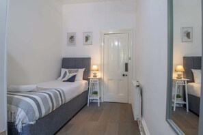 Quarto com cama, mesas de cabeceira, uma porta e obras de arte na parede.