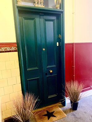 Stylish entrance with a brass doorknob and potted plants.