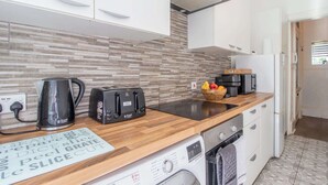 Een moderne keuken met een houten aanrecht, een waterkoker, een broodrooster, een wasmachine en een spoelbak.