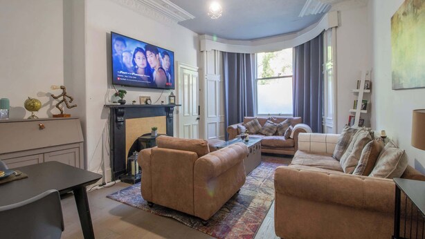 Een woonkamer met een open haard, banken, een televisie en een eethoek.