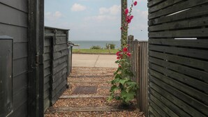 A wooden gate leading to a gravel path with a flower plant. - The Artist's Cabin By The Sea (Herne Bay)