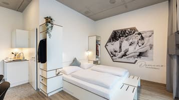 Un dormitorio moderno con cama, escritorio y espejo.