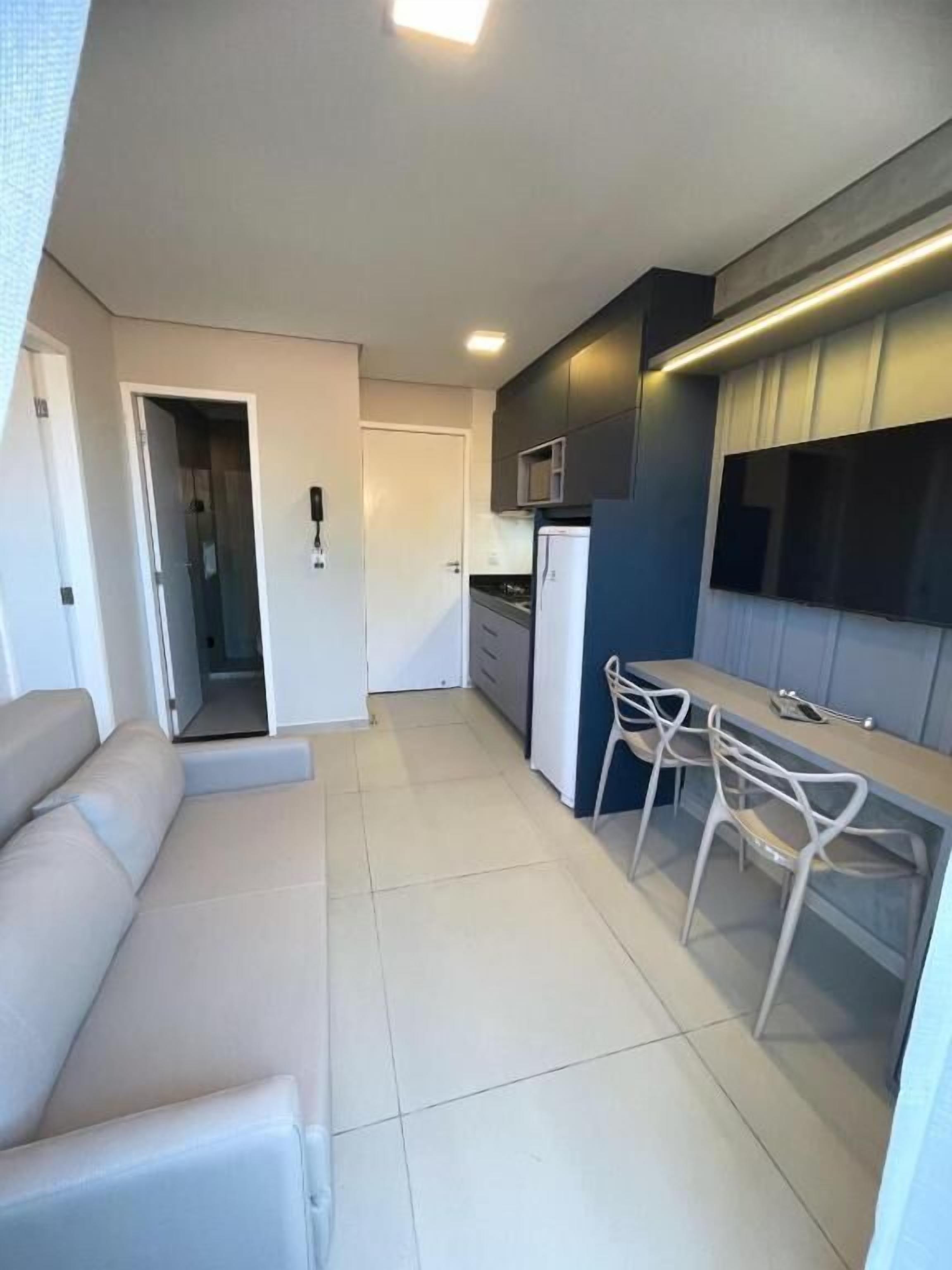 A modern kitchen with a built-in microwave, a refrigerator, and a dining area with a table and chairs.