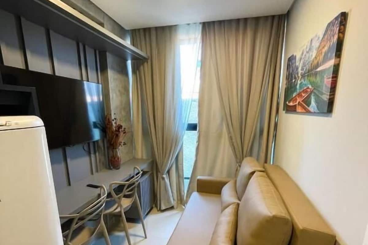 Un espacio habitable compacto con kitchenette, un sofá, un comedor y un televisor.
