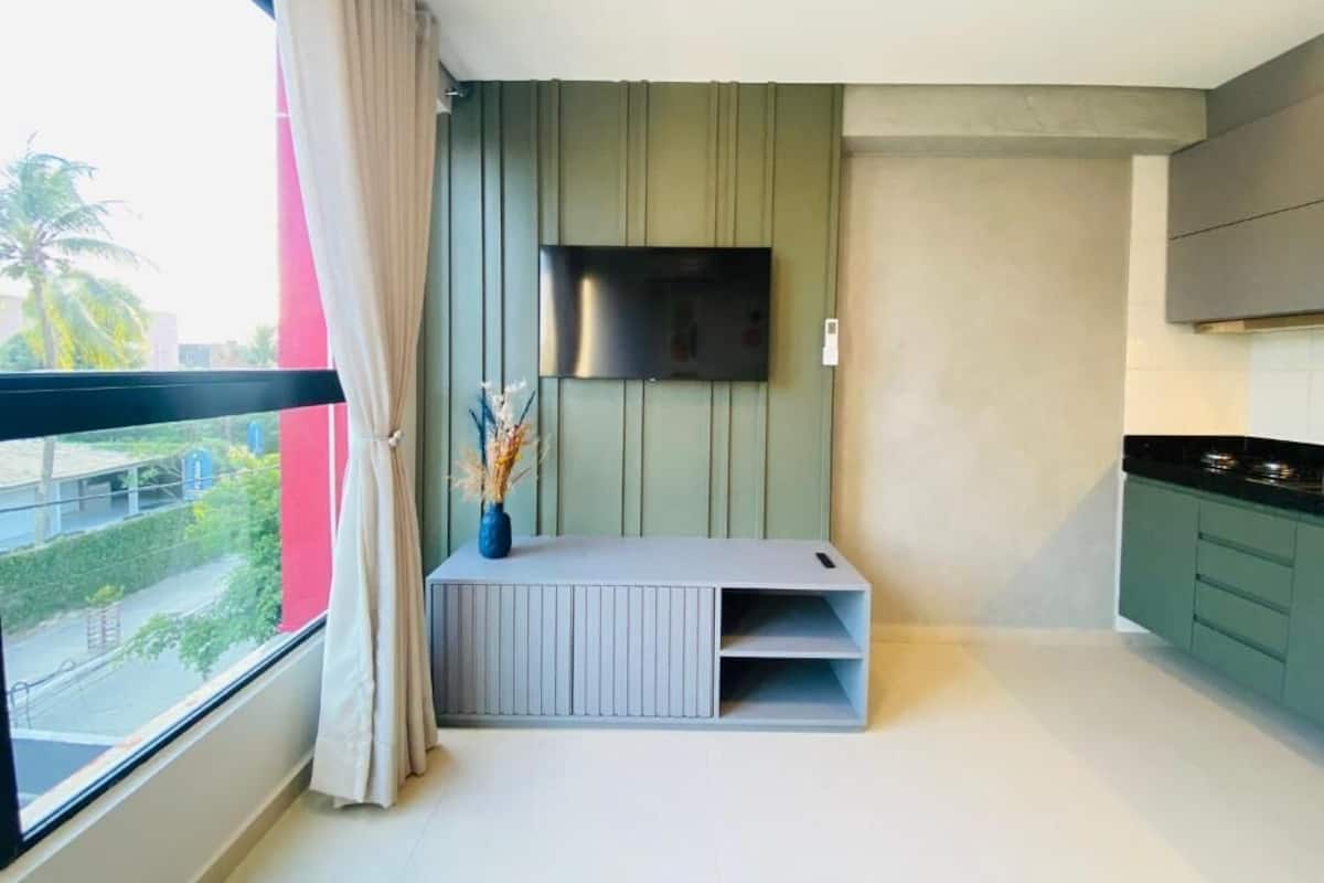 Una cocina moderna con televisor integrado, una ventana con cortinas y vistas al exterior.