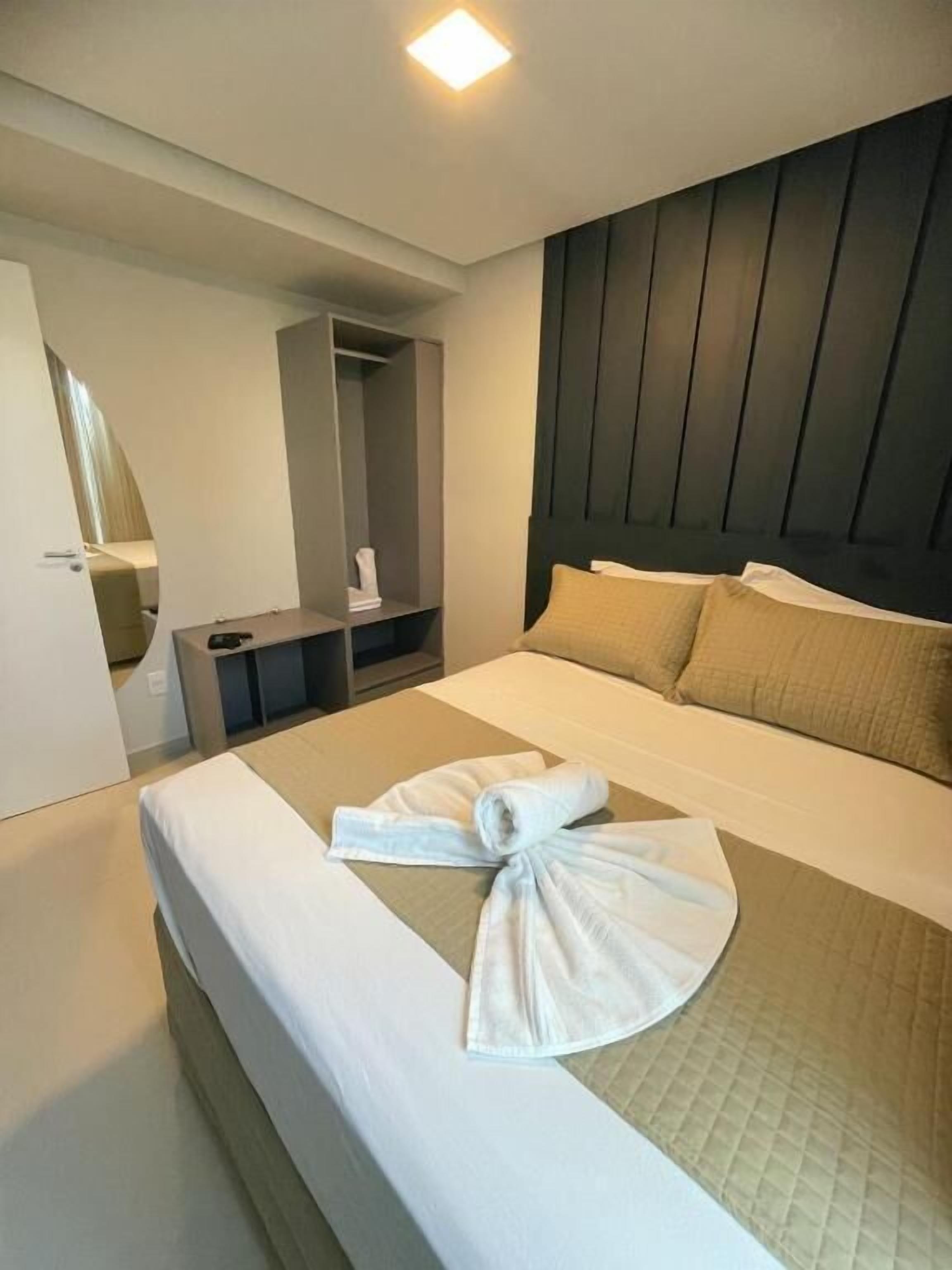 Una camera d'albergo con un letto, un comodino, un armadio e una testiera.