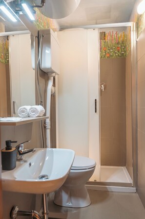 A bathroom with a sink, toilet, shower, and a mirror. - Condotta House, a private space in the heart of historical center of Florence (Firenze)