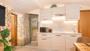 A modern kitchen with light wood cabinets, a built-in oven, and a dining area with a wooden table and chairs. - Condotta House, a private space in the heart of historical center of Florence (Firenze)