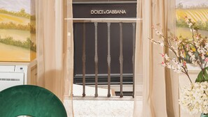 A room with a wine bottle and glasses on a table, two green chairs, and a view of a vineyard through a window. - Condotta House, a private space in the heart of historical center of Florence (Firenze)