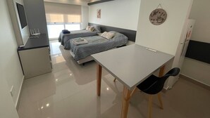 A modern, well-lit room with two beds, a desk, and a chair. - Modern & Cozy Studio in Cultural San Telmo With Pool and Exclusive Services (Buenos Aires)