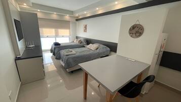 Una habitación moderna, bien iluminada, con dos camas, un escritorio y una silla.