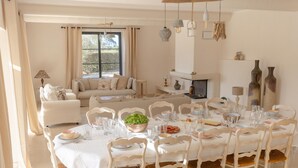 A dining area with a round table set for a meal, surrounded by white chairs with woven seats.