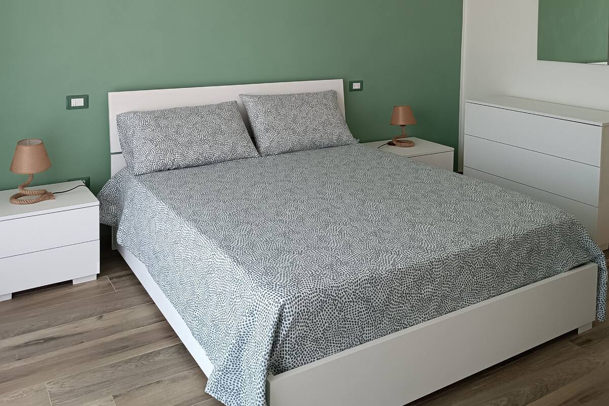 Makuuhuoneessa on sänky, yöpöydät, lipasto ja riippuvalaisin.