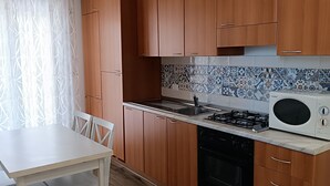 Een moderne keuken met houten kastjes, een wit aanrecht, een fornuis en een magnetron.