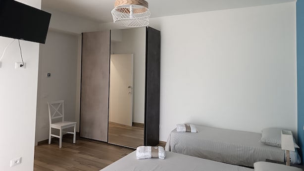 Een moderne hotelkamer met een bed, een stoel, een bureau en een televisie.