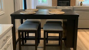 Een eetgedeelte met een donker houten tafel, vier bijpassende stoelen en een televisie boven een open haard.
