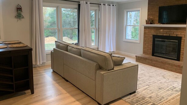 Een woonkamer met een beige bank, een houten salontafel en een open haard.