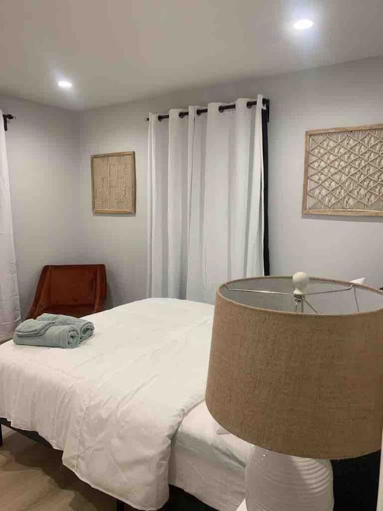 Une chambre à coucher comprenant un lit, une lampe, une chaise et deux éléments de décoration murale.