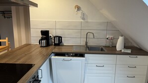 A compact kitchen with a built-in dishwasher, a stovetop, and a sink. - Urlaub auf dem Bauernhof in der Nähe von Sankt Peter Ording (Tating)