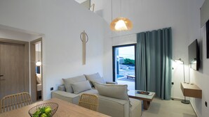Una sala moderna con una mesa de comedor de madera, un sofá, una silla de mimbre, una lámpara colgante y vistas a través de una ventana con cortinas.