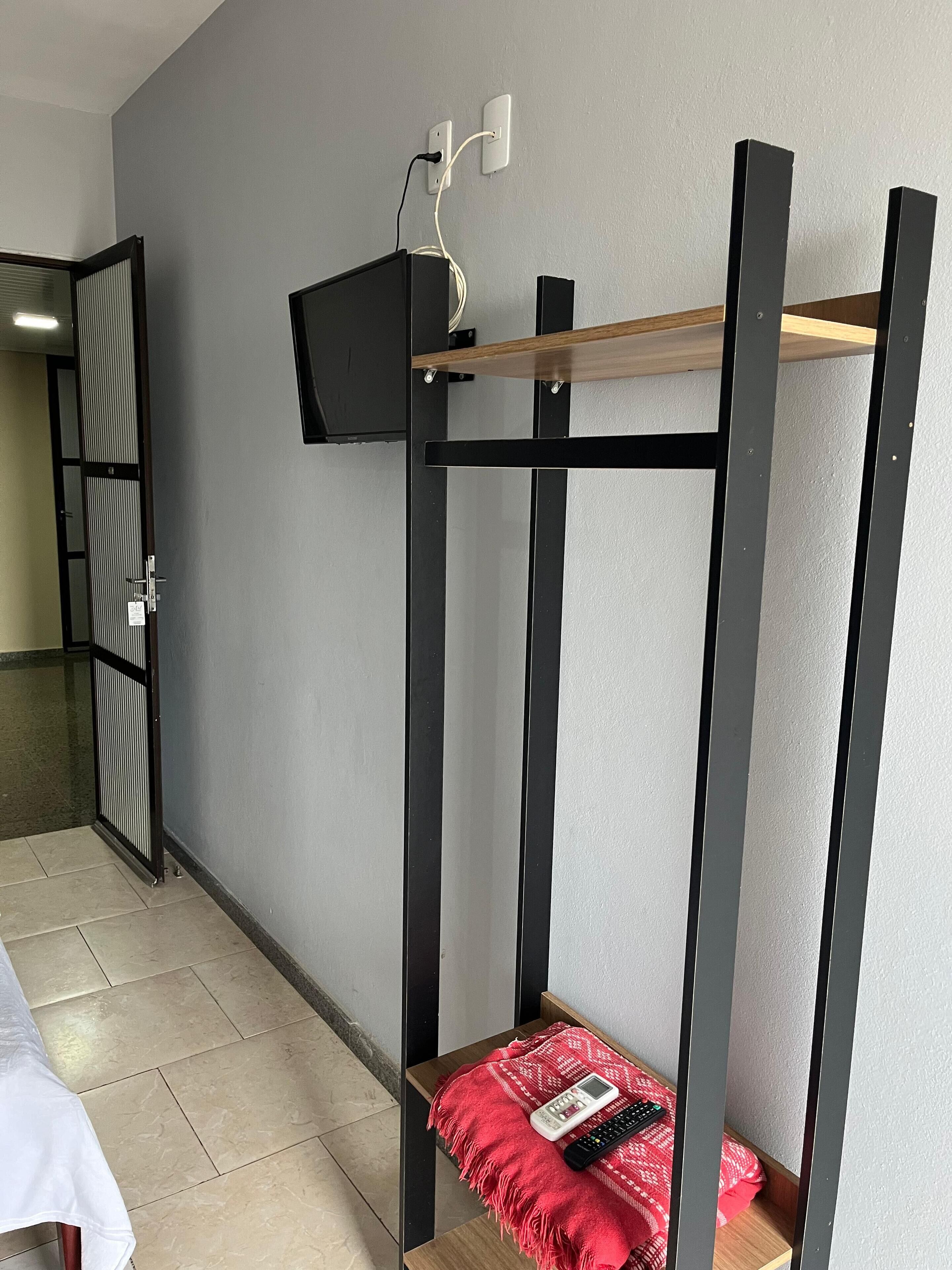 A bunk bed with a TV mounted above it, a small table with a blanket and remote control, and a door with a striped pattern.