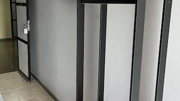 A bunk bed with a TV mounted above it, a small table with a blanket and remote control, and a door with a striped pattern.