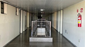 A long, narrow hallway with a central metal staircase, tiled floors, and a fire extinguisher on the right wall. - Hotel Art Final (Marataizes)