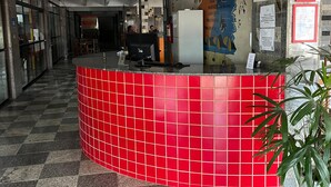 A reception area with a red tiled counter, a map on the wall, and a potted plant. - Hotel Art Final (Marataizes)