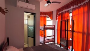 A bedroom with a bed, an air conditioning unit, a ceiling fan, and a window with red curtains. - Hotel Art Final (Marataizes)