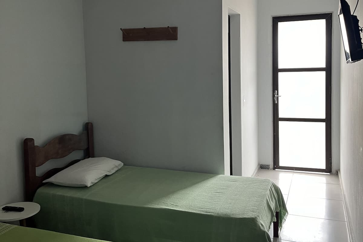 Una habitación con dos camas, ventilador de techo, ventana y puerta.