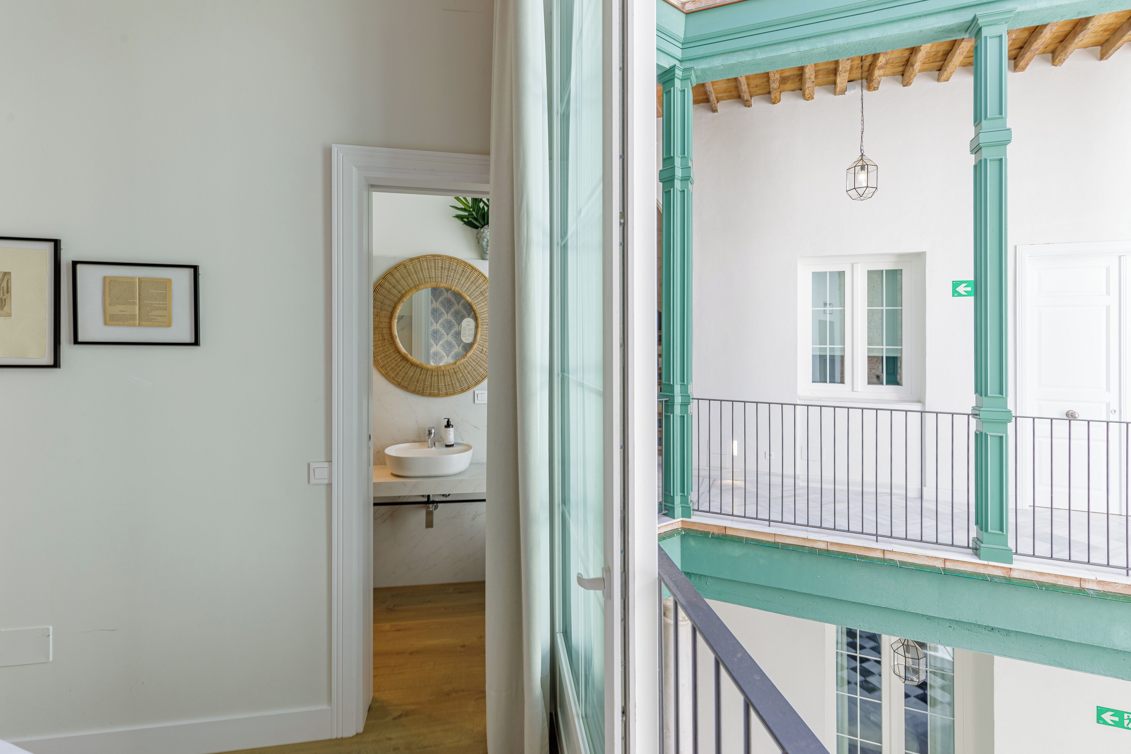 A hallway with a white door, a framed picture, a round mirror, and a sink.