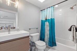 A modern bathroom with a white sink, toilet, and bathtub.